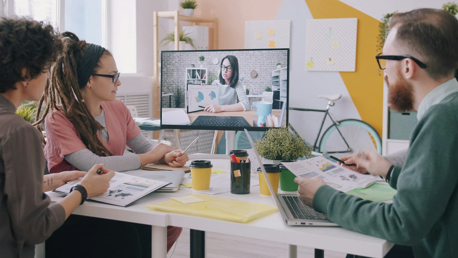 A team meeting a remote colleague over a video call in their office
